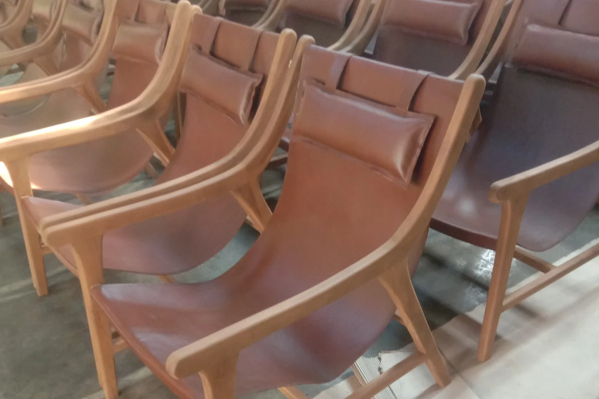 Row of finished teak and leather armchairs lined up for pre-shipment quality inspection, ExportBali