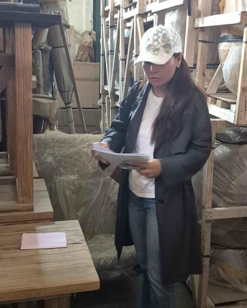 Sasha checking an order list among crated furniture before shipment