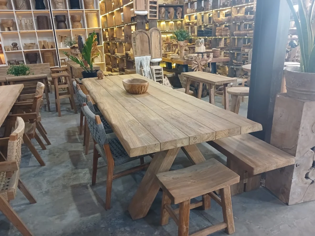 Teak plank dining table with benches in a Bali furniture showroom